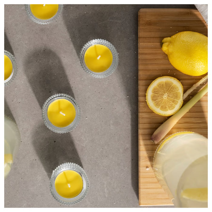 IKEA BLODHÄGG scented tealight – lemon & lemongrass/yellow, candles with lemongrass and lemonade on gray surface - 30571507