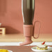 Pink rubber boot with a cup holder on a wooden surface with a blurred background