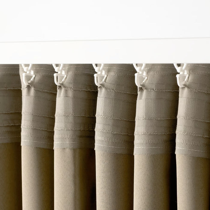 Curtain system detail showing pleated beige fabric attached to sliding track with plastic hooks