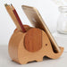 Wooden elephant-shaped phone stand with a phone and pencil on a light background