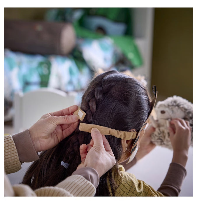 Person braiding a child's hair with a blurred indoor background