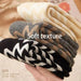 Stack of four folded zigzag fleece socks in cream, gray, brown, and black with “Soft texture” label