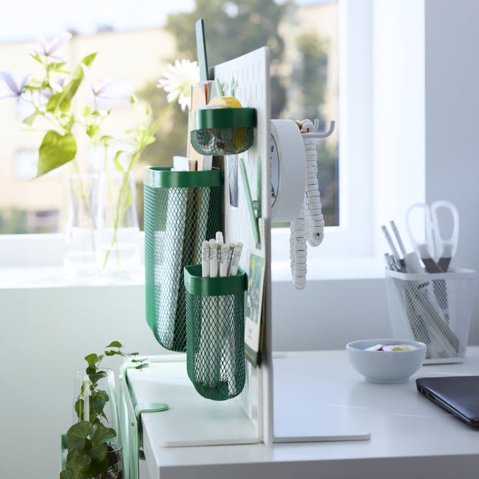 IKEA SKÅDIS green mesh storage basket set of 3 mounted on white pegboard; organizing pens, pencils, tape, and stationery in bright workspace with plants, laptop, and window view – ideal for creative desk setup - 20597471