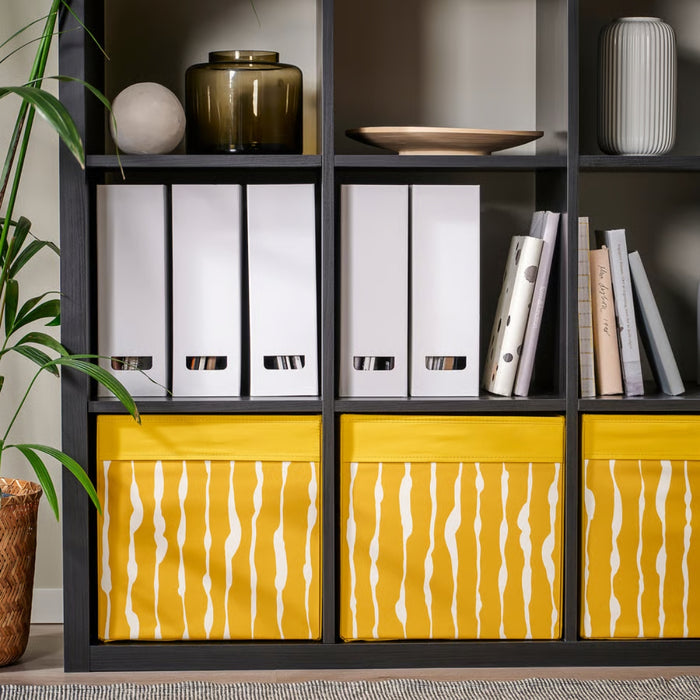IKEA DRÖNA Box in dark yellow with white wavy-line design, neatly placed on a white shelf, storing folded clothes and accessories—ideal for stylish home organization.-00603331
