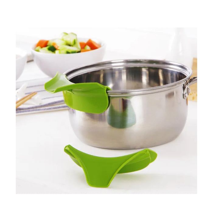 Green pot holder on a stainless steel pot with a bowl of vegetables in the background