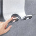 Hand interacting with metallic wall hook mounted on gray tiled surface