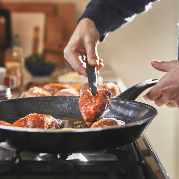 Person cooking meat in a pan on a stove