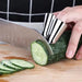 Metal finger cot guards worn while slicing cucumber – protective kitchen tool for safe vegetable cutting – 771727