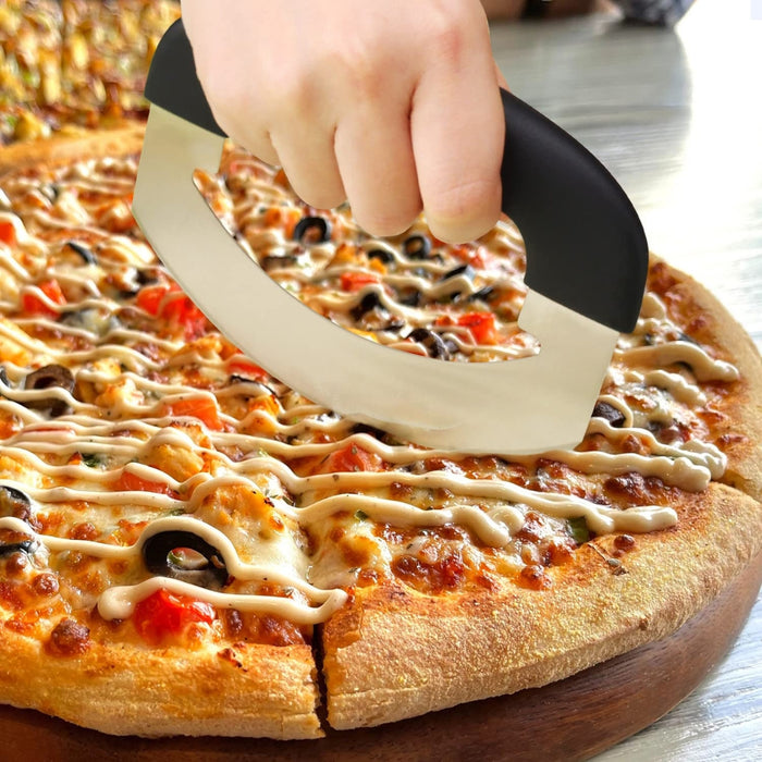 Hand using a pizza cutter to slice a pizza with various toppings on a wooden board.