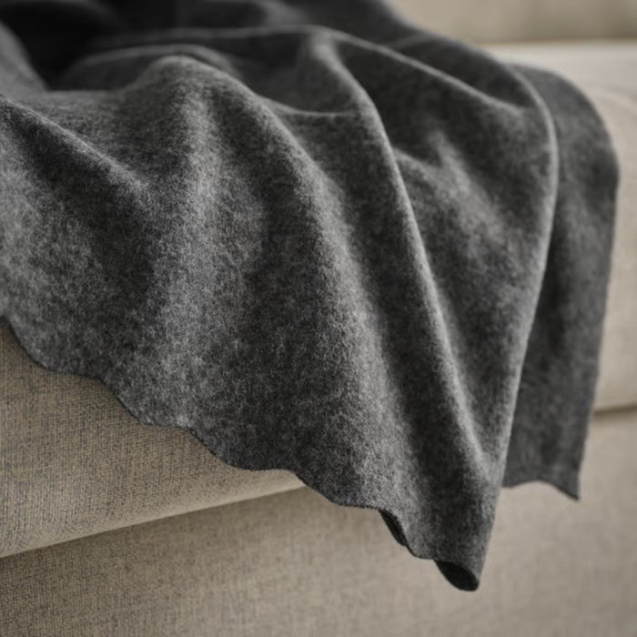 DAGGKÅPOR throw, dark grey, 130x170 cm. Soft textured fabric draped over beige sofa edge – warm and cosy accent for living space or reading nook – 50598643.