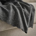DAGGKÅPOR throw, dark grey, 130x170 cm. Soft textured fabric draped over beige sofa edge – warm and cosy accent for living space or reading nook – 50598643.