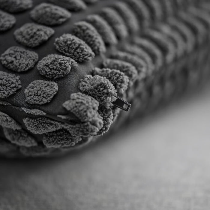  Detailed view of SVARTPOPPEL cushion cover with plush tufted dot pattern and visible zipper at edge for removable cover convenience