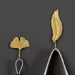 Gold leaf hooks – mounted in bathroom holding white towels beside ceramic sink