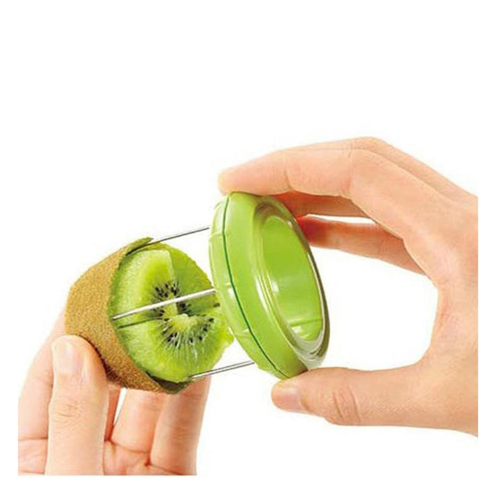 A green and silver kiwi slicer and corer being demonstrated by two hands, with a sliced kiwi held in one hand and the tool pressed into it against a white background.