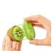 A green and silver kiwi slicer and corer being demonstrated by two hands, with a sliced kiwi held in one hand and the tool pressed into it against a white background.
