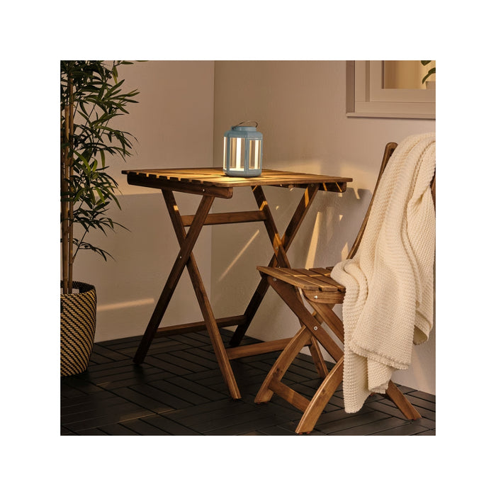 Wooden table and chair set with a lantern on a wooden deck