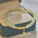 Green beaded bracelet with a gold charm on a blue surface