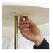 Hand adjusting a gold ceiling fixture against a neutral background