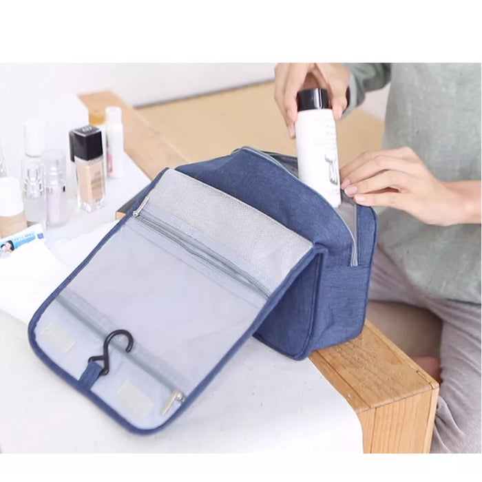 Travel storage waterproof bag, blue. Shown open on table as person places bottle inside – mesh pocket with zipper, hanging hook, and toiletries make packing feel effortless – 13403615.