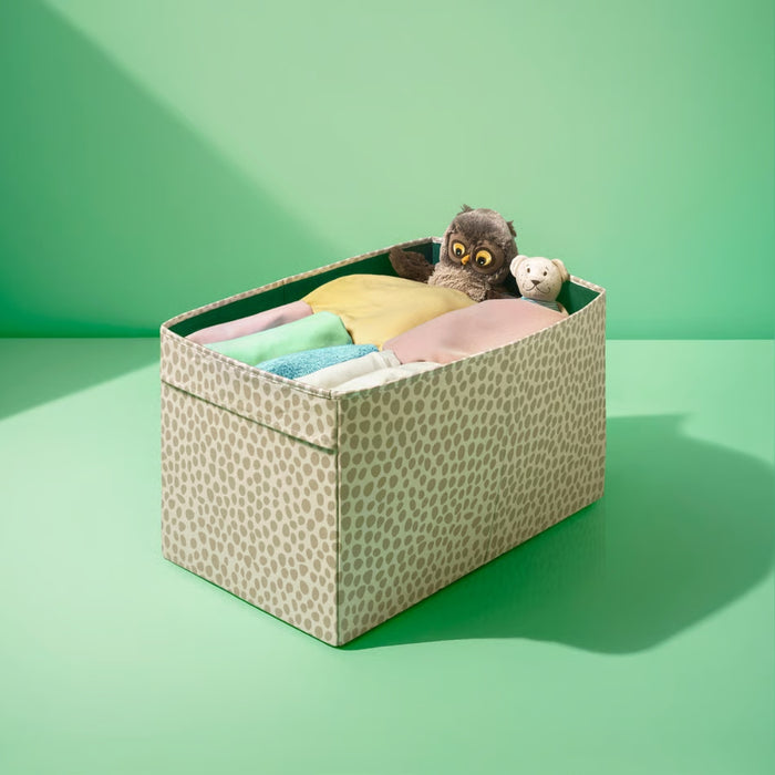 Storage box with patterned lid containing colorful items on a green background