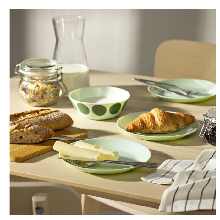Table setting with plates, bread, and croissants on a wooden table.