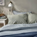 Bed with striped bedding and pillows in a bedroom setting.
