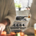 Person cooking in a kitchen with a stove and pots in the background