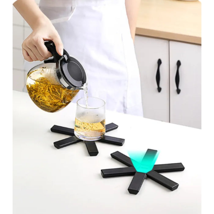 Person pouring tea into a glass on a kitchen counter with glowing black coasters.