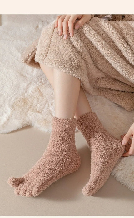 Person wearing fluffy pink socks with a soft beige blanket in the background