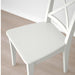 White chair on a wooden floor with a white wall in the background