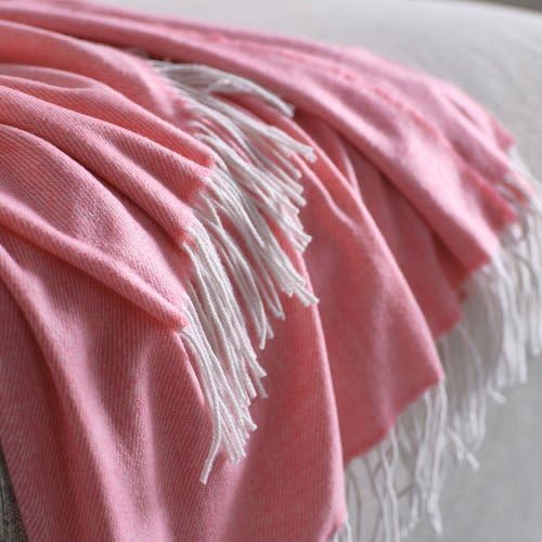 Close-up of the IKEA HOLMVI throw in pastel pink—white fringes cascade neatly from the edge, with the woven texture clearly visible and the blanket draped gracefully over a soft gray surface. The gentle folds and delicate weave showcase its lightweight and cozy appeal, ideal for layering in bedrooms, lounges, or reading corners – 00604689.