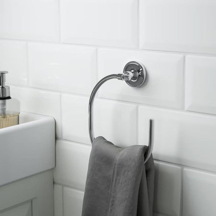 Towel rack with a gray towel against a white tiled bathroom wall.