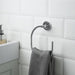 Towel rack with a gray towel against a white tiled bathroom wall.