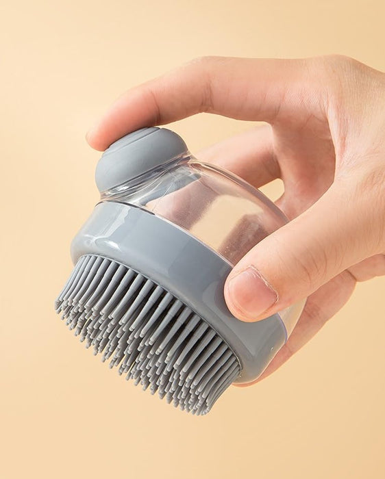 Hand holding a gray silicone scalp massager brush with a transparent container for shampoo or liquid. Soft silicone bristles gently massage the scalp, enhancing circulation and deep cleaning during hair care routines- 159845334888512362182