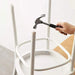 Person using a hammer on a white chair frame.