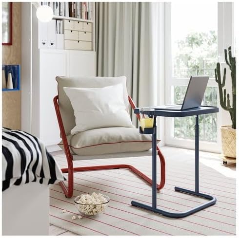 IKEA BJÖRKÅSEN laptop stand in blue featured in a cozy room setting—placed in front of a cushioned chair with red frame, the stand holds an open laptop and a glass of juice. – 90607358.