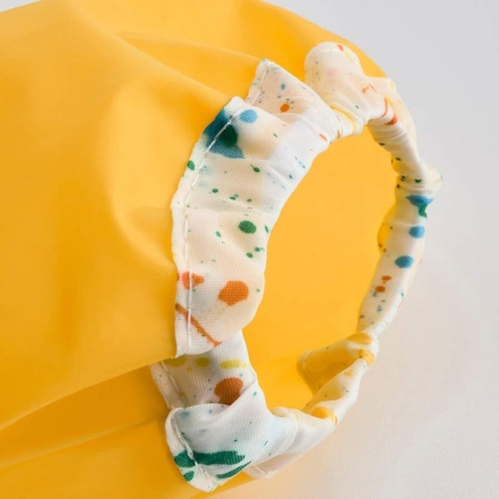 Yellow bath pillow with a polka dot headband on a white background