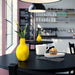 Yellow vase with a flower on a black table in a kitchen setting