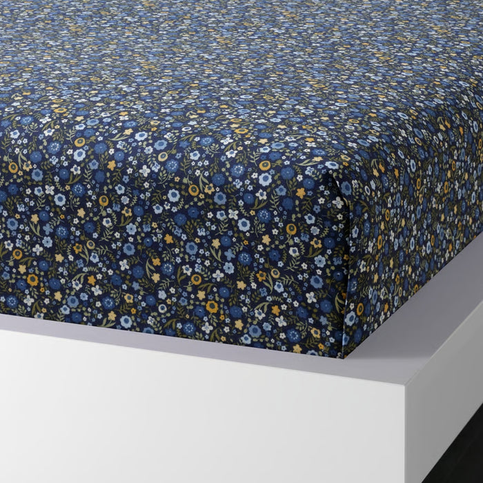 Floral patterned fitted sheet on a bed with a white frame