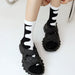Close-up of feet in black sandals and white socks with abstract black wave pattern