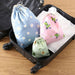 Open suitcase with three fabric drawstring bags, including blue floral, pink frog, and green avocado designs – 1598445710448 14078092