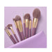 Set of makeup brushes with gold accents on a purple background