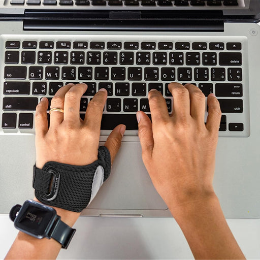 Person typing on a laptop with a wrist support device on one hand