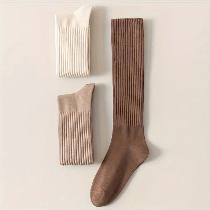 Three pairs of ribbed socks in white, beige, and brown arranged on flat surface