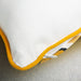 Close-up of a white pillow with yellow trim on a neutral background