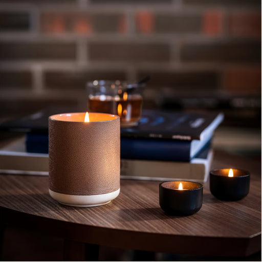 Lit IKEA SILKESTRÄD scented tealights in black and brown holders with leather and vanilla fragrance; cozy setup on wooden table with books and warm drink – 3.5-hour burn time, 30-pack - 20570551