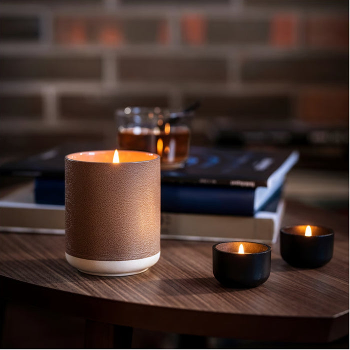 Lit IKEA SILKESTRÄD scented tealights in black and brown holders with leather and vanilla fragrance; cozy setup on wooden table with books and warm drink – 3.5-hour burn time, 30-pack - 20570551
