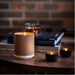Lit IKEA SILKESTRÄD scented tealights in black and brown holders with leather and vanilla fragrance; cozy setup on wooden table with books and warm drink – 3.5-hour burn time, 30-pack - 20570551
