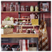 Kitchen counter with jars, vegetables, and kitchen utensils against a red wall.