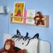 Children’s bedroom with zebra pillow and orangutan plush toy sitting on the bed, another hanging from a wall shelf.